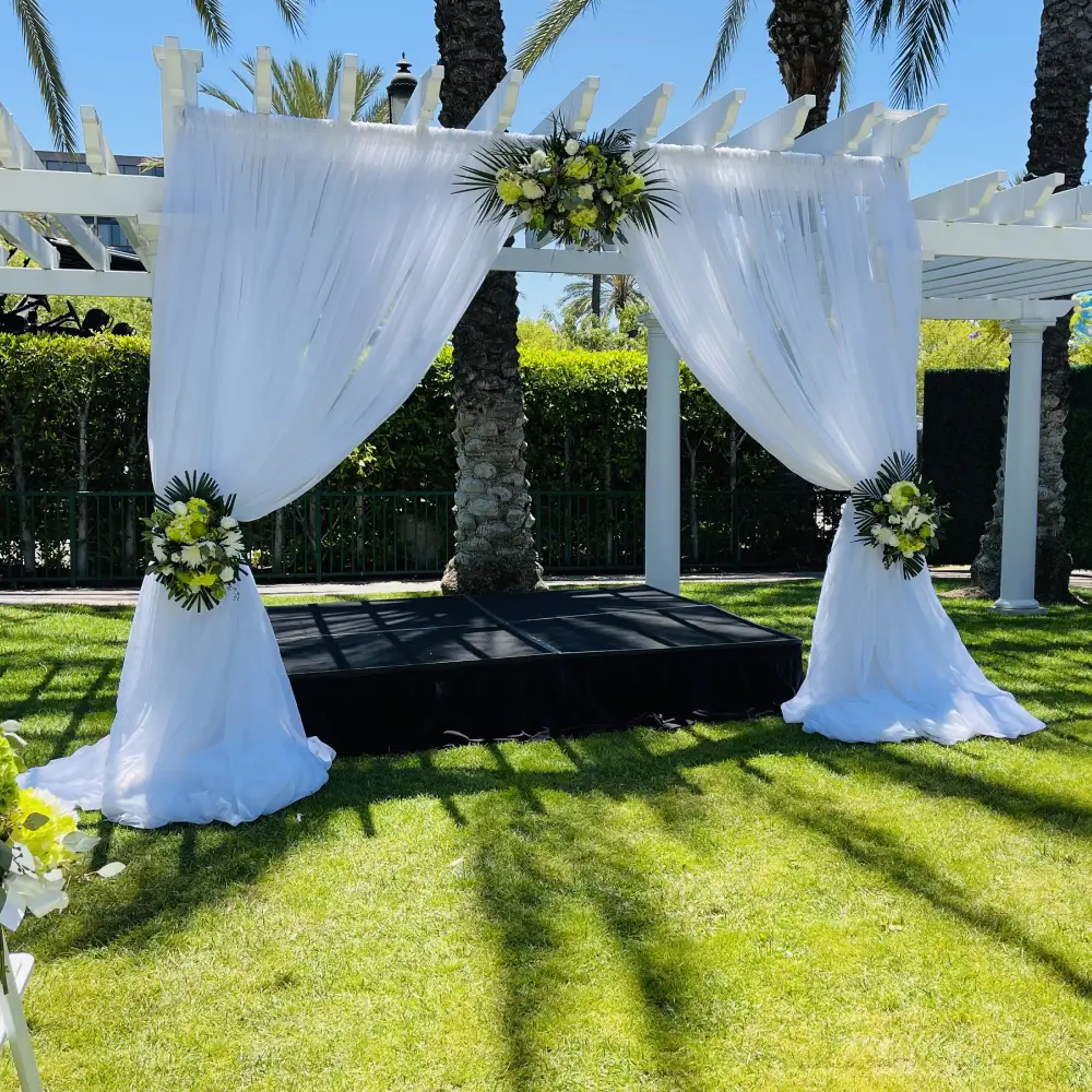 Outdoor wedding ceremony gazebo with white drapery and florals