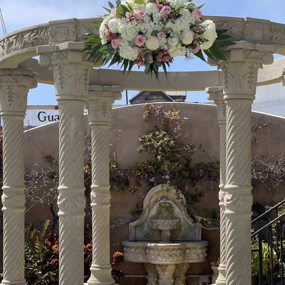 Classical stone gazebo adorned with elegant wedding floral swag