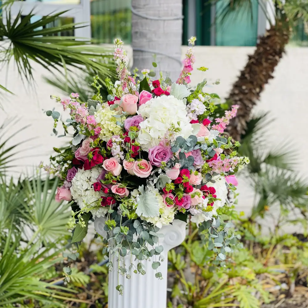 Outdoor pedestal centerpiece with pink roses and greenery