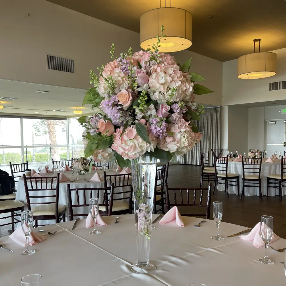 Tall trumpet vase floral centerpiece in reception hall