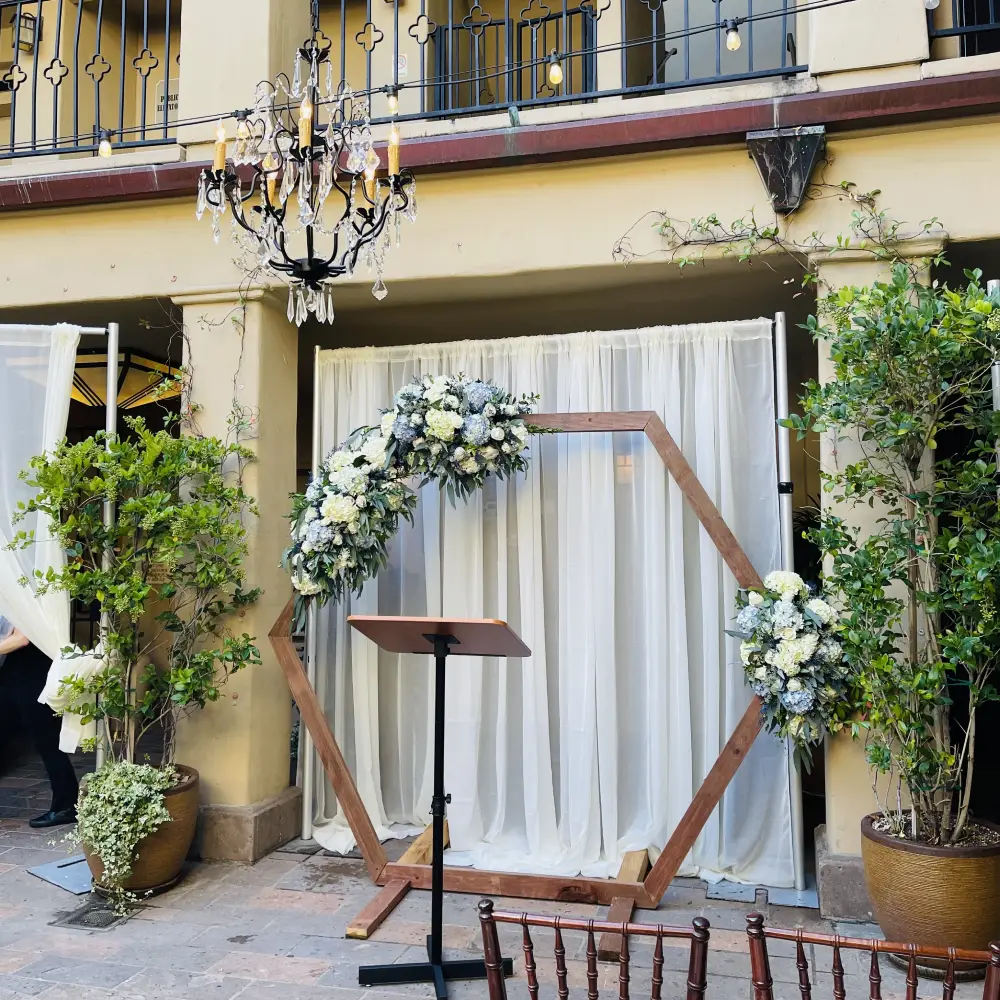 Hexagonal wedding arch adorned with white floral sprays